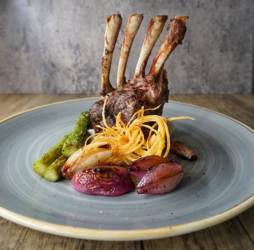 Beautifully plated rack of lamb served with roasted asparagus, caramelized shallots, and crispy fried onions, prepared by a private chef in Tenerife.