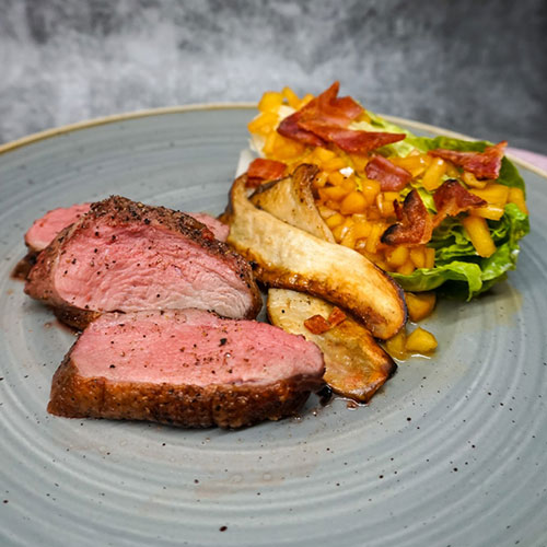 Tender sliced duck breast accompanied by roasted root vegetables and a fresh salad with crispy bacon, prepared by a private chef in Tenerife.