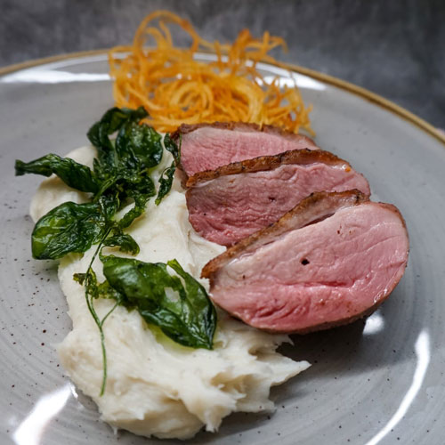 Succulent sliced duck breast served with creamy mashed potatoes, crispy spinach, and golden fried carrot strands, prepared by a private chef in Tenerife.