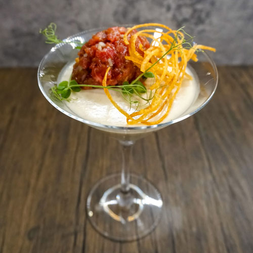 Gourmet dessert in a martini glass featuring a creamy base topped with a savory meatball and crispy fried carrot strands, garnished with microgreens, created by a private chef in Tenerife.