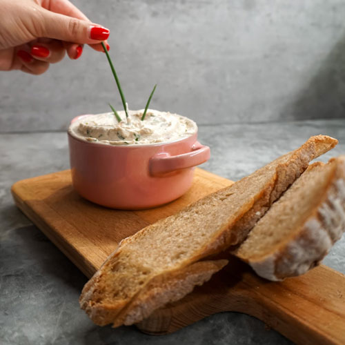 Homemade dip served in a pink bowl, garnished with chives, accompanied by slices of rustic homemade bread on a wooden board, prepared by a private chef in Tenerife.