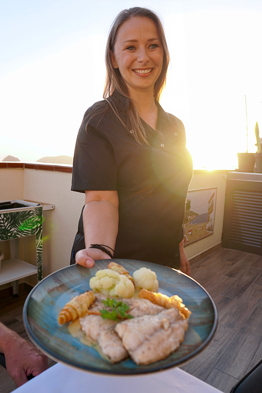Private chef Janine in Tenerife serving freshly prepared fish fillet with cauliflower and root vegetables at sunset.