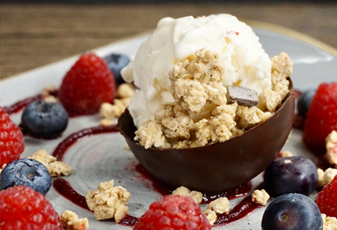 White chocolate mousse in a dark chocolate cup with granola, fresh berries, and raspberry coulis, prepared by a private chef in Tenerife.