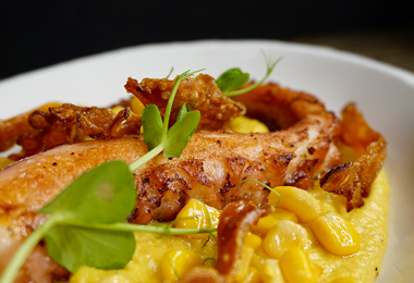 Grilled octopus tentacle with crispy garnish on creamy corn purée, prepared by a private chef in Tenerife.