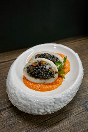 Stuffed squid with black rice and vegetables on a red pepper sauce, prepared by a private chef in Tenerife.
