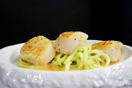 Seared scallops served on zucchini noodles with a light sauce, prepared by a private chef in Tenerife.